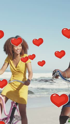 Vertical video: Woman on pink bike, man cycling, pedaling on beach, sparking red hearts, marketing. Bicycle, couple, coastal, romance, sunny, outdoor, vertical video