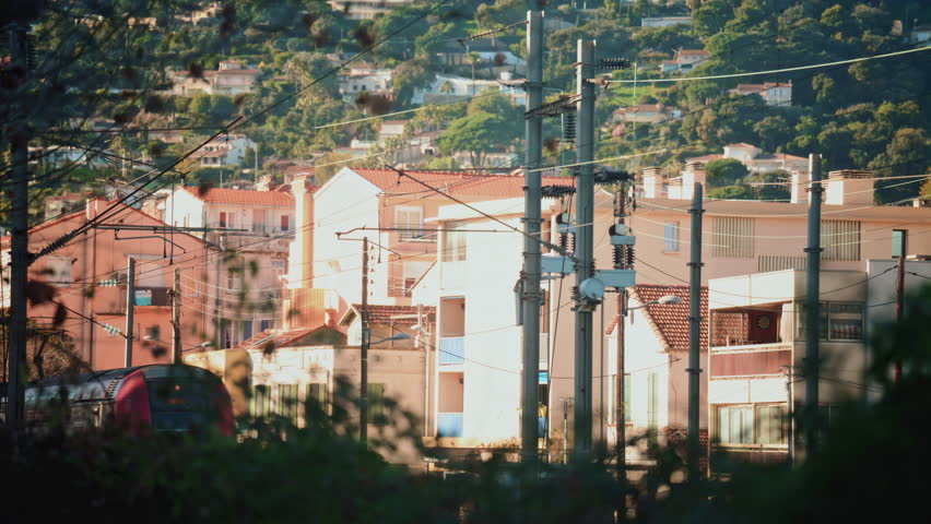 Close up of an electric train passing beneath overhead power lines and utility structures