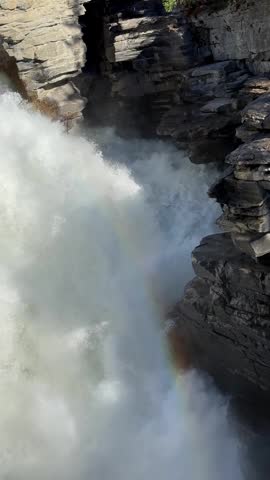 Athabasca Falls rainbow forming over natural rocky canyon in Jasper national park, Canada