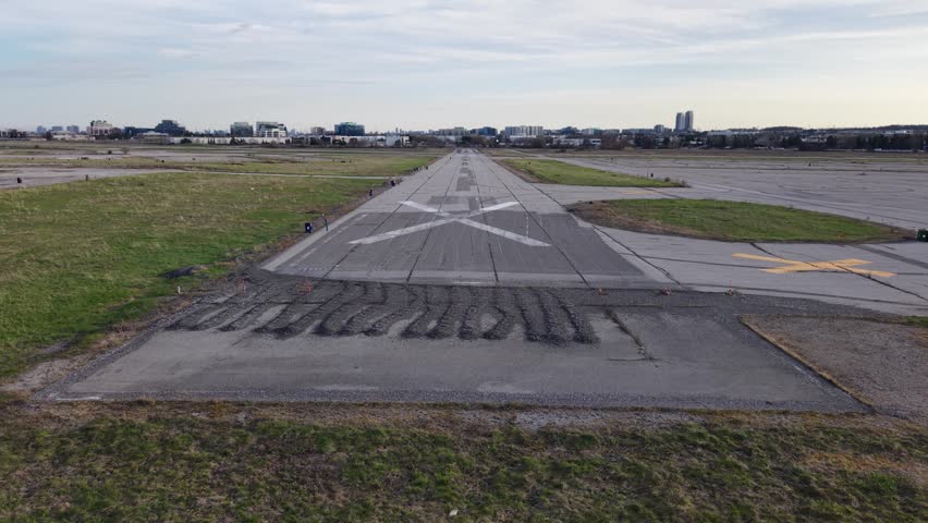 A forward-moving aerial shot taking off from the closed runways of Buttonville Airport, rising to reveal the busy Highway 404 and industrial landscape in Markham, Ontario