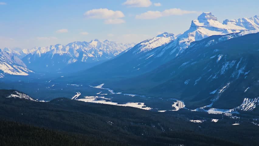 Mountain landscape resembling Jasper National Park features sweeping forest, braided river flats, and distant snowcovered peaks, creating a dramatic and highly marketable nature scene.