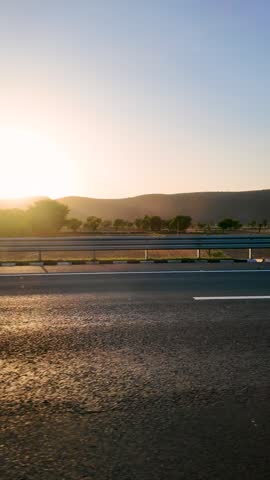 Golden sunlight bathes the highway, creating a warm glow on the asphalt and highlighting the surrounding vegetation. The scene evokes a sense of peaceful travel.