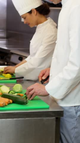 Group of chefs talking cooking and slicing vegetables in a restaurant kitchen