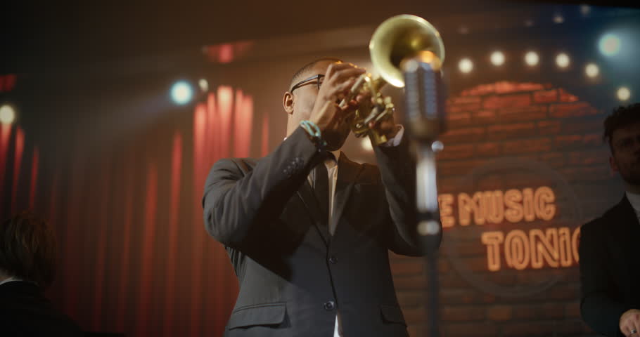 Portrait of Black Male Trumpeter Doing Solo Live Jazz Band on a Bar Stage, Playing a Soulful Song at a Concert Event While the Audience Enjoys the Music. Moving Stylish Medium Closeup