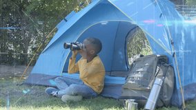 Boy sitting tent entrance raising binoculars and scanning trees and sky for outdoor birdwatching. Child, camping, shelter, yard, grass, backpack, fence - Powered by Shutterstock - Get 15% off with code: PIKWIZARD15