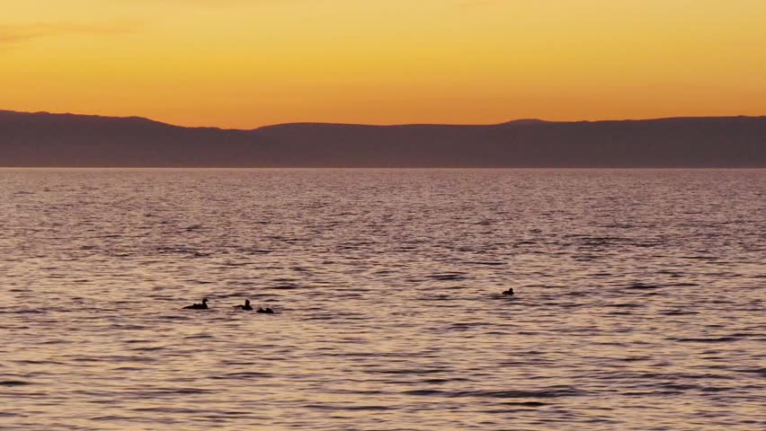 Sunset on Lake Baikal in Russian Siberia on a chilly autumn evening. The orange sky is reflected in the calm surface of the lake.