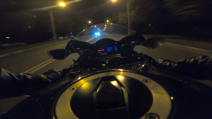 Point of view of motorcycle rider rides in evening town road in high speed. The viewpoint of motorcyclist driving in the night empty city streets. Guy racing bike during trip. Concept of freedom. POV