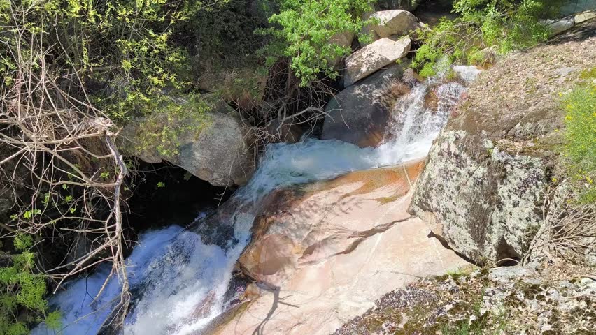 Crystal-clear stream winding through granite cliffs and riparian vegetation amidst nature