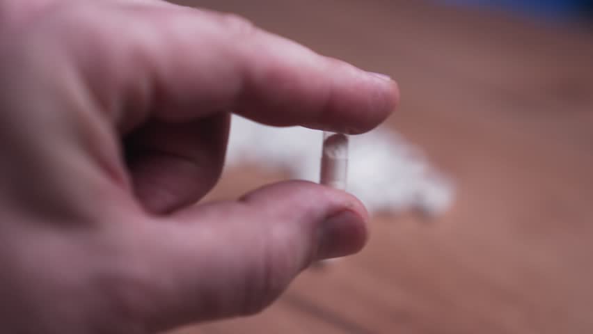 The fingers hold one pill, a capsule with a vitamin or medicine. Medical concept, demonstration of pills.