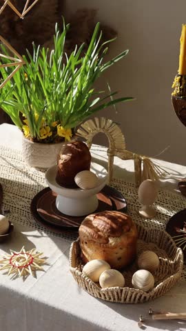 Traditional festive Easter table with Easter bread, spring flowers, candles and handmade Ukrainian straw decoration. Holiday celebration, family traditions and seasonal decor concept.