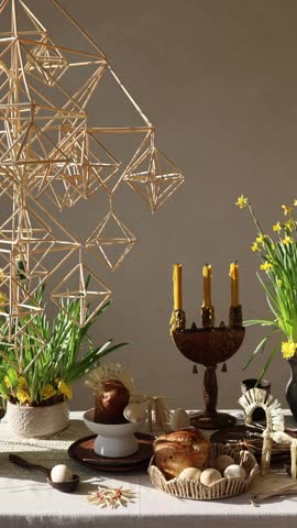 Traditional festive Easter table with Easter bread, spring flowers, candles and handmade Ukrainian straw decoration. Holiday celebration, family traditions and seasonal decor concept.