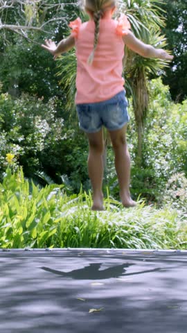 Blonde girl doing back flip on trampoline in the garden