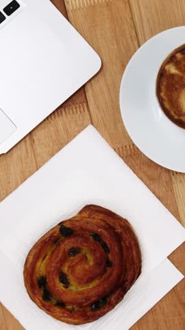 Close-up of laptop with coffee cup and sweet cookie on wooden table 4k