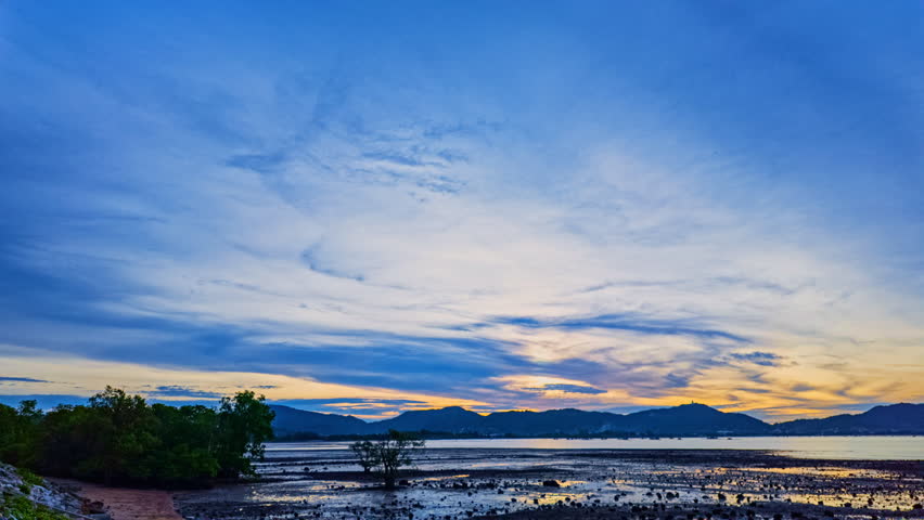 A stunning scene of a vivid sunset with pink and orange hues illuminating the sky over a tranquil rocky shoreline. The silhouetted mountains and serene water create a peaceful and atmospheric view