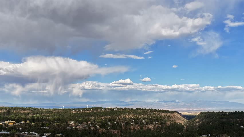 4K drone timelapse captures dramatic rain clouds shifting over the high-altitude landscape of Los Alamos, New Mexico. The rapid atmospheric motion over the Pajarito Plateau moody atmosphere.