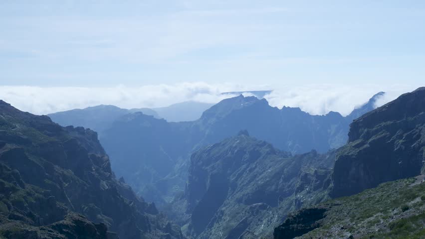 Scenic view of a mountain valley with clouds rolling over the peaks