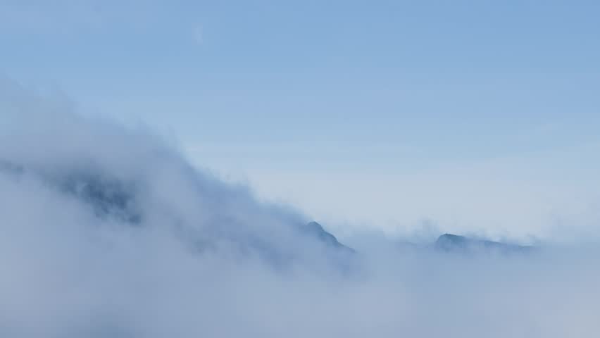 White clouds moving over a majestic mountain peak
