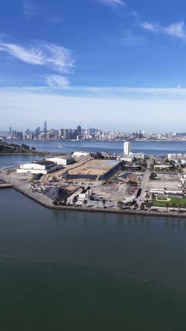 Aerial drone view flying over treasure island in the San Francisco bay, showing the iconic city skyline with modern skyscrapers and beautiful clouds on a bright sunny day in California