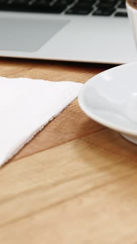 Close-up of laptop with coffee cup and sweet cookie on wooden table 4k