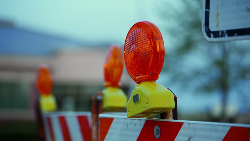 Road construction barrier with flashing warning lights. Traffic safety equipment on street during maintenance or repair work.