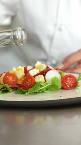 Chef puting olive oil on a fresh salad