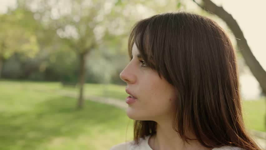 Beautiful young woman smiling and looking at the camera in a sunny park