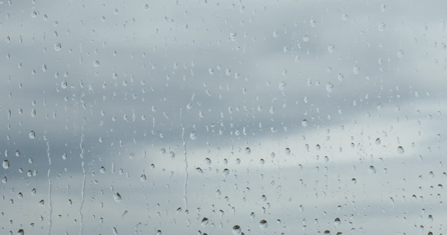 Window with water drops. View on cloudy sky through wet glass