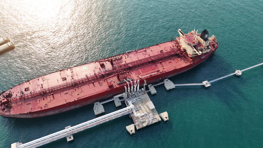 large red oil tanker docked at an offshore terminal for petroleum loading in the Strait of Hormuz. Global energy supply chain, maritime logistics, and