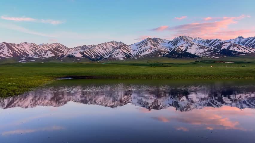 Beautiful sunset view with pink clouds reflecting in a clear alpine lake in Xinjiang China.