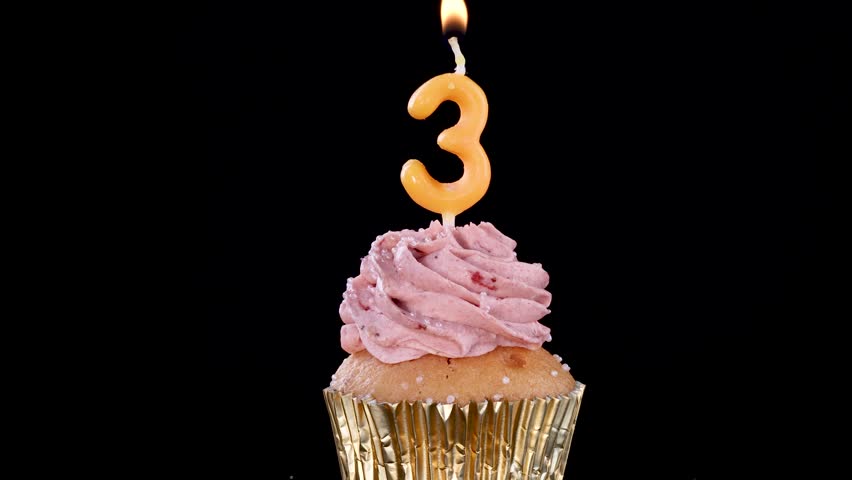 Tasty muffin with pink cream and flickering candle light.