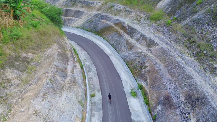 Aerial View of Man Riding Bicycle on Winding Road