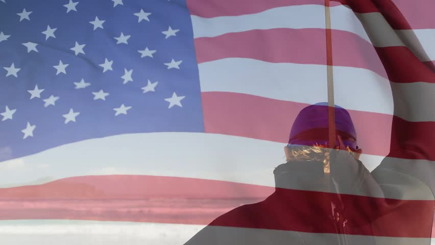 Man standing right facing ocean, lifting pole and aligning American flag overlay for education. Silhouette, backlit, banner, beach, horizon, seascape, breezy