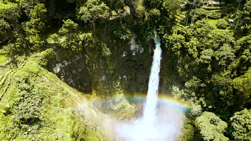 A multi-stage waterfall descending through a vibrant tropical mountain gorge in Lake Sebu, South Cotabato, Philippines, cascading into a serene pool with misty forest basin views.