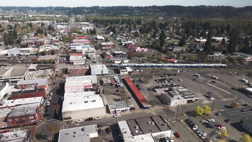Aerial View Of Passenger Train Passing Through Commercial And Residential Area In Downtown Puyallup, Washington. tracking shot
