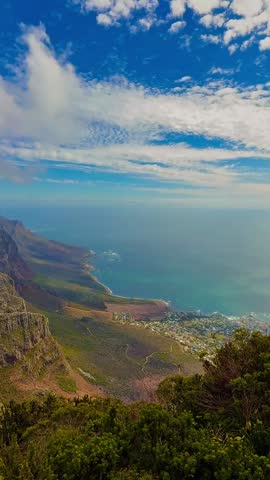 Panoramic summer view from Table Mountain over Cape Town, featuring dramatic mountain landscapes, the Atlantic Ocean coastline, and native fynbos vegetation.