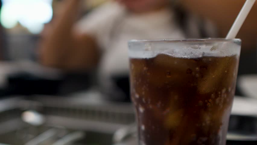 Static close-up of a refreshing iced cola drink on a table at a buffet