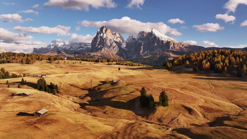 Field with wooden houses. Alpe di Siusi, Seiser Alm, aerial view of majestic dolomites, mountains background.