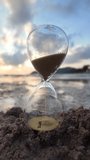 An hourglass on the beach with gentle waves flowing around it at sunset. Concept of passing time, fleeting moments, life transition, and time management. 4K slowmotion footage. - Powered by Shutterstock - Get 15% off with code: PIKWIZARD15