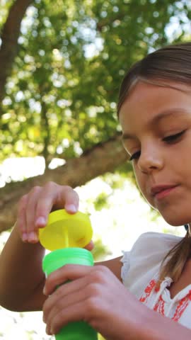 Cute girl blowing bubbles through bubble wand in park 4k