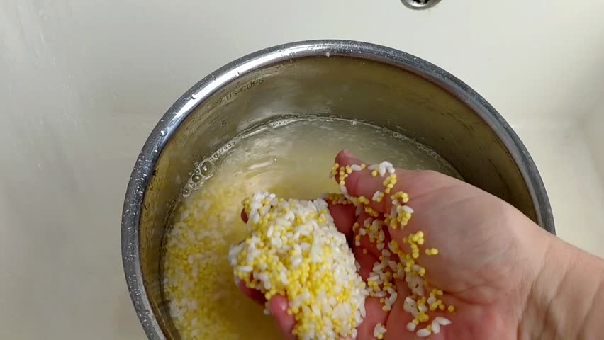 A woman rinses rice and millet in a pot under running water, close-up.