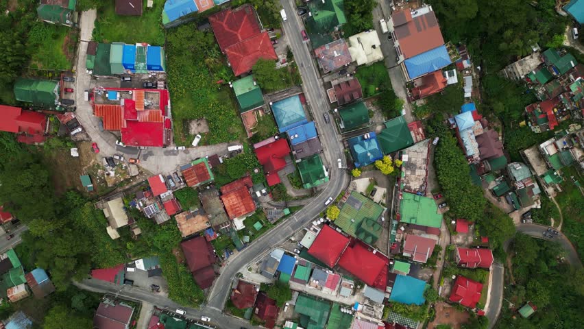 Aerial top-down view of a compact hillside neighborhood with colorful rooftops and a winding road cutting through Quirino Hill in Baguio City, Philippines