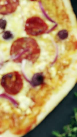 Overhead of italian pizza on wooden table with vegetables and spices