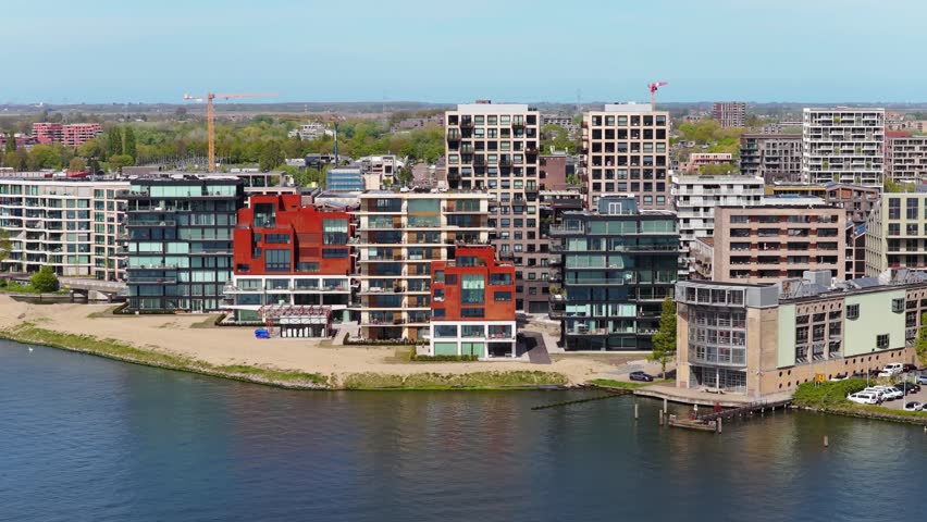 Aerial perspective of modern real estate developments and contemporary apartment buildings along riverbank showcasing Amsterdam