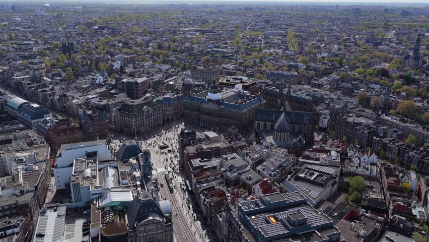 Flight revealing royal palace of Amsterdam on Dam Square, Nieuwe Kerk, historic city center with charming houses and urban infrastructure on sunny day