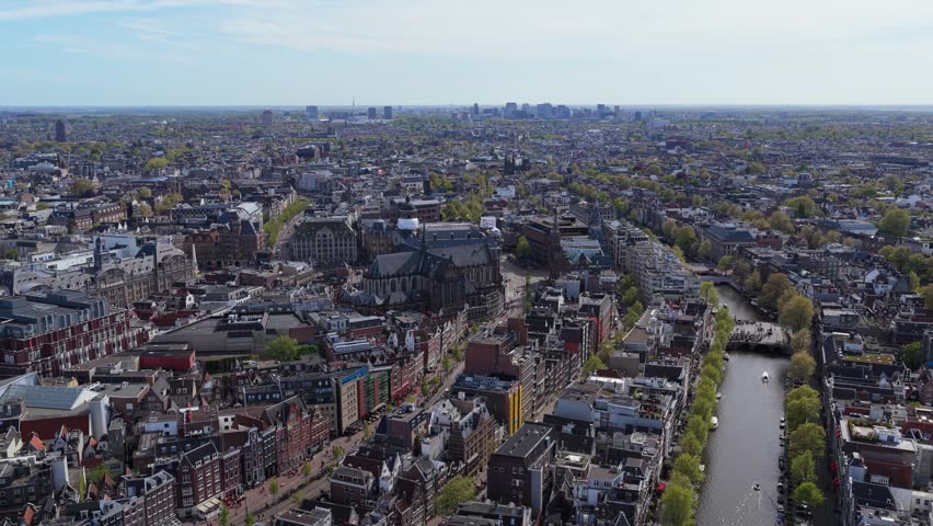 Amsterdam cityscape showcasing historic architecture, city canals and traditional Dutch houses with boats sailing along Singelgracht under bright spring sunshine in Holland