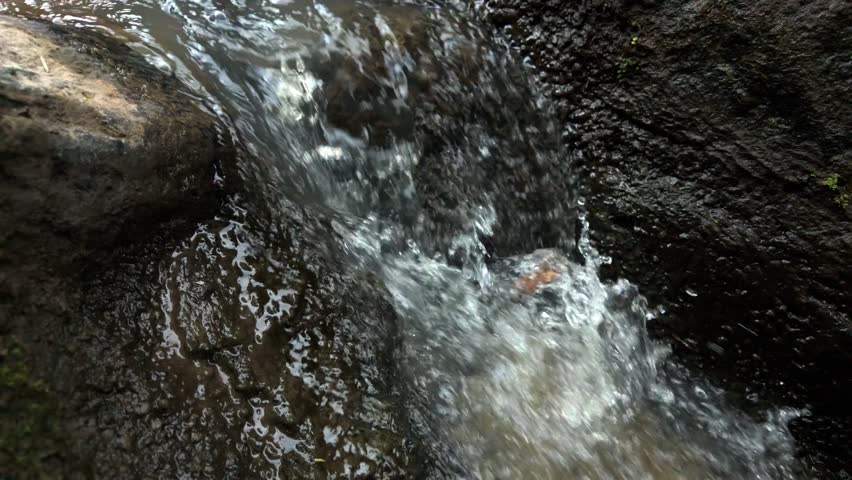 Close Up of Clear Water Rushing Over Wet Rocks