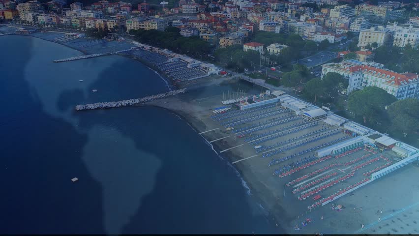 HUD squares fading from left, drifting and settling over shore, showing resort data. Aerial, coastal, beach, promenade, sunbeds, umbrellas, overlay