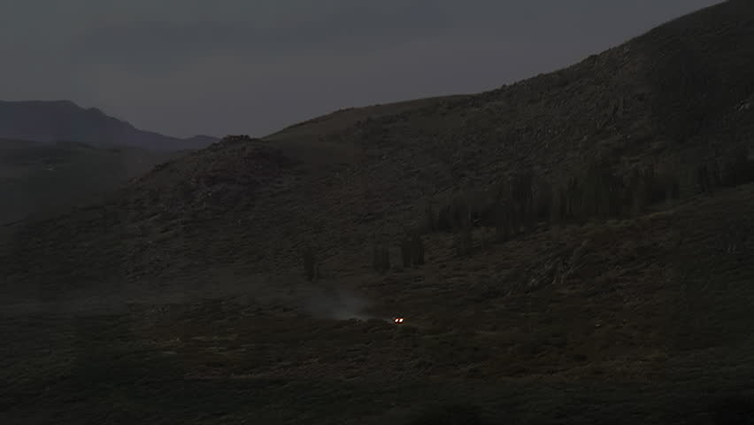 Two Cars with Headlights Illuminating Remote Mountain Landscape at Night
