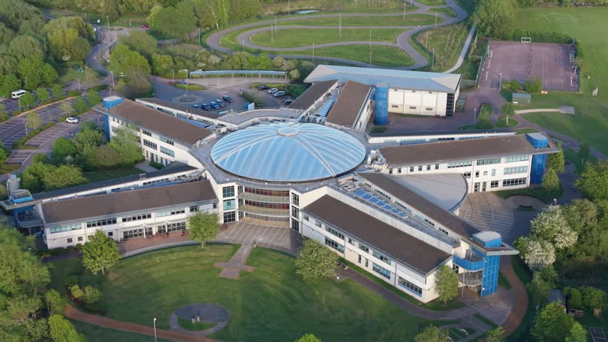 Aerial drone footage of a modern academy building in Swindon, Wiltshire, showcasing contemporary educational architecture and surrounding urban landscape