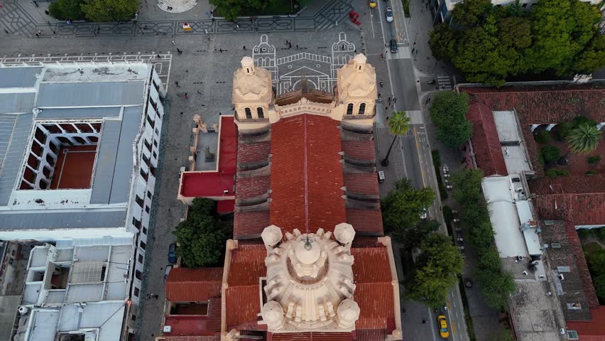 Aerial drone shot slowly pulling back from the top of the cathedral of cordoba, revealing the main facade and san martin square in argentina